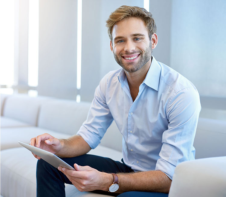 A man sitting on top of a couch holding an ipad.