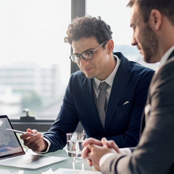 Two men in suits looking at a laptop